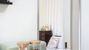 A room with a light green sofa, a wooden cabinet, and two glass jars with lids on a table. - Sevenhouse by Atlantic Holiday (Machico)