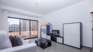 A modern living room with a grey sofa, a black coffee table, a TV, and a wardrobe. - 1 Bedroom apartment Paraiso Sol da Rocha (Portimão)