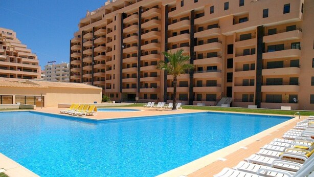 A swimming pool with lounge chairs and a building in the background. - 1 Bedroom apartment Paraiso Sol da Rocha (Portimão)