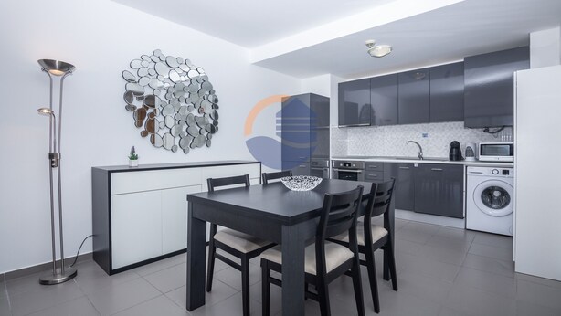Een moderne keuken met donkere kastjes, een witte aanrecht en een ingebouwde wasmachine.