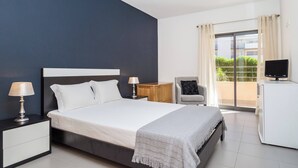 A modern bedroom with a bed, bedside tables, a chair, a TV, and a balcony with a view. - 1 Bedroom apartment Paraiso Sol da Rocha (Portimão)