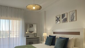 A hotel room with a bed, a bedside table, a lamp, a mirror, and artwork on the wall. - 1 Bedroom apartment Paraiso Sol da Rocha (Portimão)