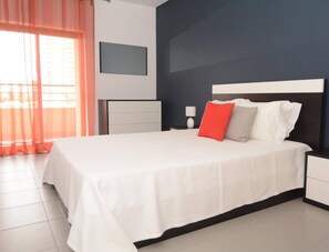 Relax in a spacious room with a large bed, flat-screen TV, and a nightstand with a lamp.