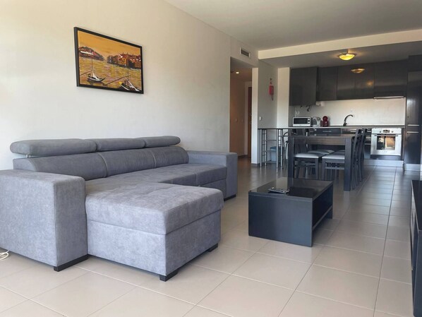 Relax in this stylish living room with a large L-shaped sofa, coffee table, and framed coastal artwork.