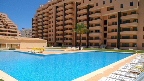 A swimming pool with lounge chairs and a building in the background. - 3 Bedroom apartment Paraiso Sol da Rocha (Portimão)