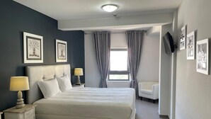 A modern bedroom with a large bed, bedside lamps, a chair, and artwork on the walls. - 3 Bedroom apartment Paraiso Sol da Rocha (Portimão)