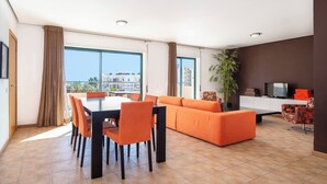 A modern living room with a dining area, large windows, and a view of the city. - 3 Bedroom apartment Paraiso Sol da Rocha (Portimão)
