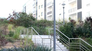Un escalier avec des rampes en métal menant à un immeuble à plusieurs étages doté de balcons.