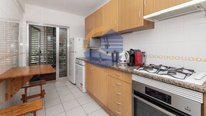Eine Küche mit Holzausstattung, einem Gasherd, einer Mikrowelle, einem Spülbecken und einem Esstisch mit Bänken.