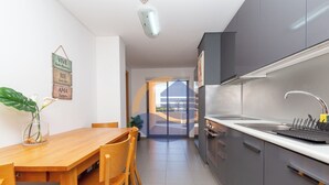 A modern kitchen with grey cabinets, a stainless steel sink, and a wooden dining table with chairs. - 3 Bedroom apartment Paraiso Sol da Rocha (Portimão)