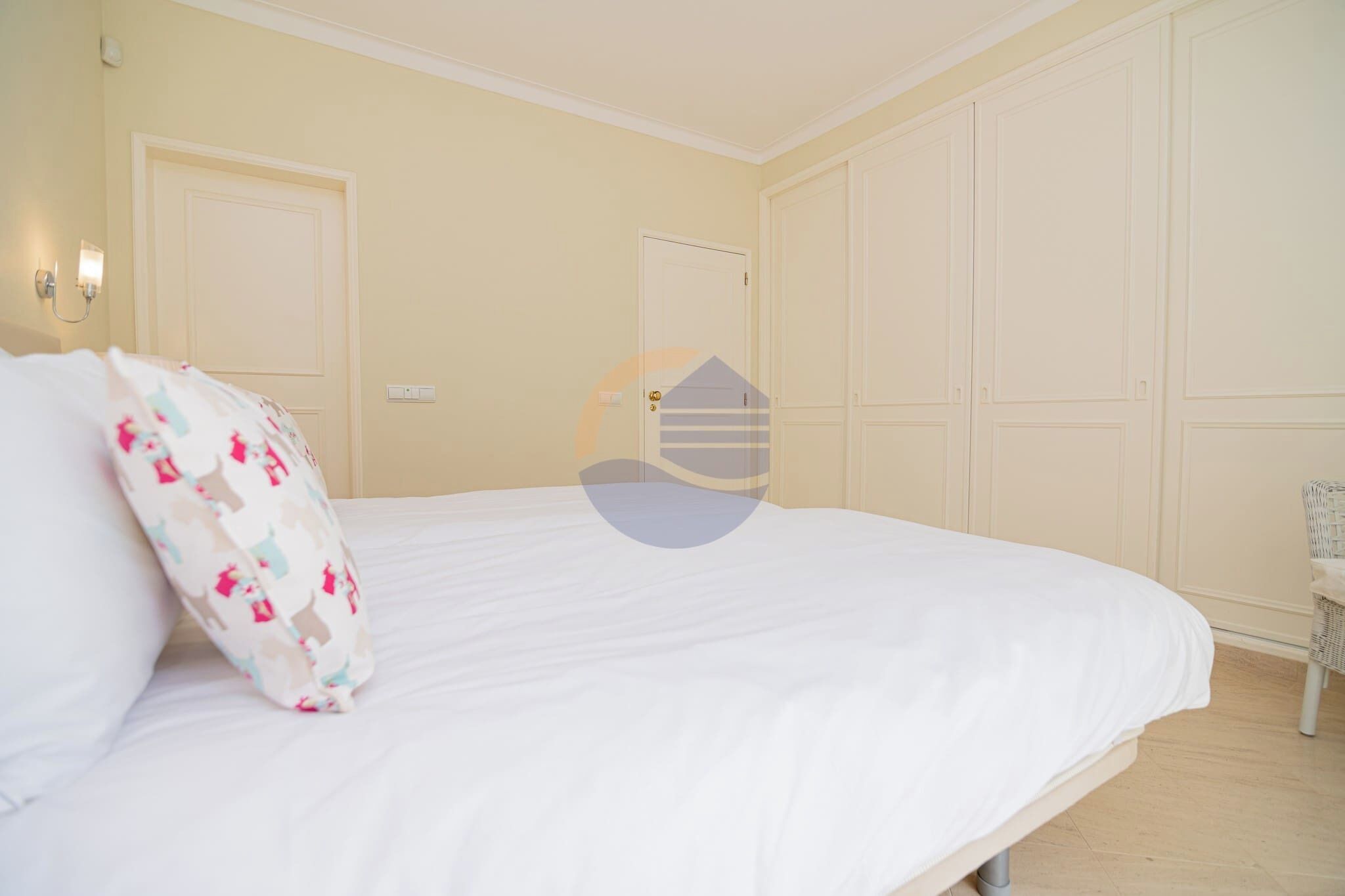 A bedroom with a large bed, a door, and a wardrobe.