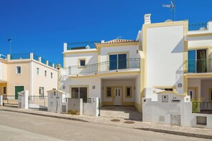Un immeuble résidentiel à plusieurs étages, doté de balcons, d’une entrée sécurisée et surplombant un ciel d’un bleu éclatant.