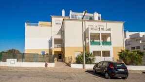 A multi-story residential building with a car parked in front.