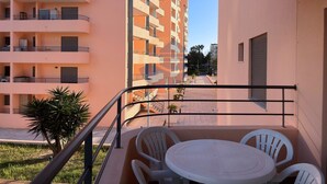 A balcony with a table and chairs, overlooking a courtyard with a building in the background. - 1 Bedroom apartment Paraiso Sol da Rocha (Portimão)