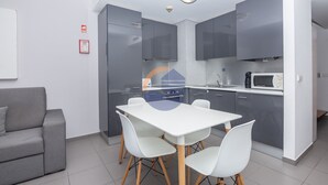 A modern kitchen with grey cabinets, a white dining table, and white chairs. - One bedroom Duplex Paraíso Sol da Rocha (Portimão)