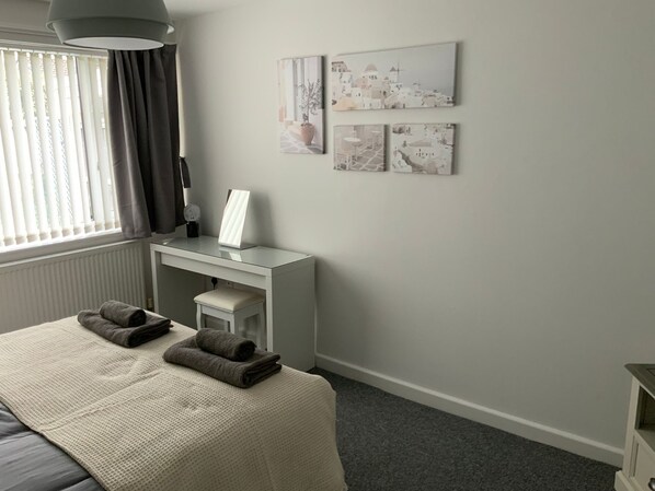 A bedroom with a bed, a desk, a chair, and a radiator.