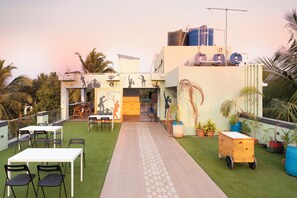 Eine Dachterrasse mit Tischen, Stühlen, einem Weg und Topfpflanzen.