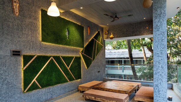 Un interior moderno con un diseño geométrico en la pared, paneles de césped artificial verde y bancos de madera.