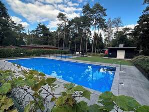 Relax by the rectangular pool surrounded by a paved deck and lush greenery.