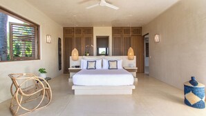Un dormitorio amplio con una cama grande, un ventilador de techo y vistas al exterior a través de una ventana.