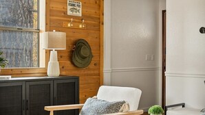 Una sala de estar acogedora con paredes de madera, una chimenea, un sofá, una mesa de centro y un letrero de advertencia sobre la enfermedad de los pescadores.