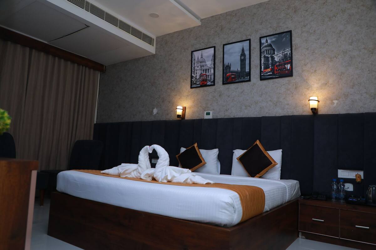 A hotel room with a large bed, two wall-mounted lamps, and three framed pictures of London landmarks.