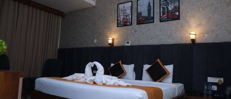 Een hotelkamer met een groot bed, twee wandlampen en drie foto’s in lijsten van bezienswaardigheden in Londen.