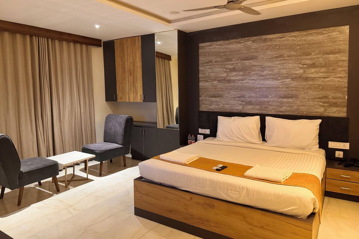 A modern hotel room with a large bed, a desk, a chair, and a ceiling fan.