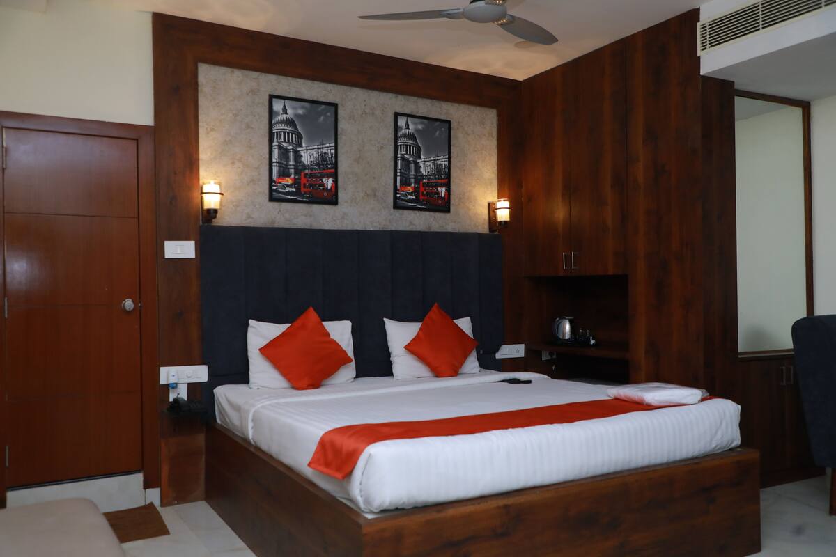 A hotel room with a wooden bed, two wall-mounted lamps, and a ceiling fan.