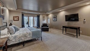 Une chambre à coucher avec un lit, un bureau, une chaise, un téléviseur et une grande fenêtre.