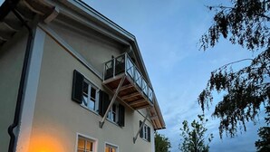 A two-story building with a balcony, a gravel driveway, and a view of the sky. - Bloom | small, cozy apartment with lake access to Wörthsee & WLAN (Wörthsee)