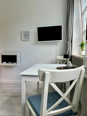 Enjoy a compact space for dining, entertainment, and relaxation with a flat-screen TV, dining table, and potted plant.