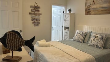 A bedroom with a bed, pillows, a wall decoration, a fish sculpture, and a door.