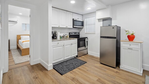 A compact kitchen with white cabinets, a microwave, a stove, and a refrigerator. - Casa Roselle  (Hollywood)