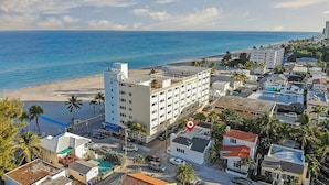 A coastal hotel with multiple floors, a beach view, and a parking area with cars. - Casa Roselle  (Hollywood)