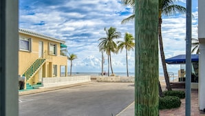 A beachfront property with a staircase leading to a balcony, palm trees, and a view of the ocean. - Casa Roselle  (Hollywood)