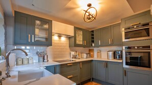A modern kitchen with grey cabinets, a white countertop, and stainless steel appliances including a built-in oven and microwave.