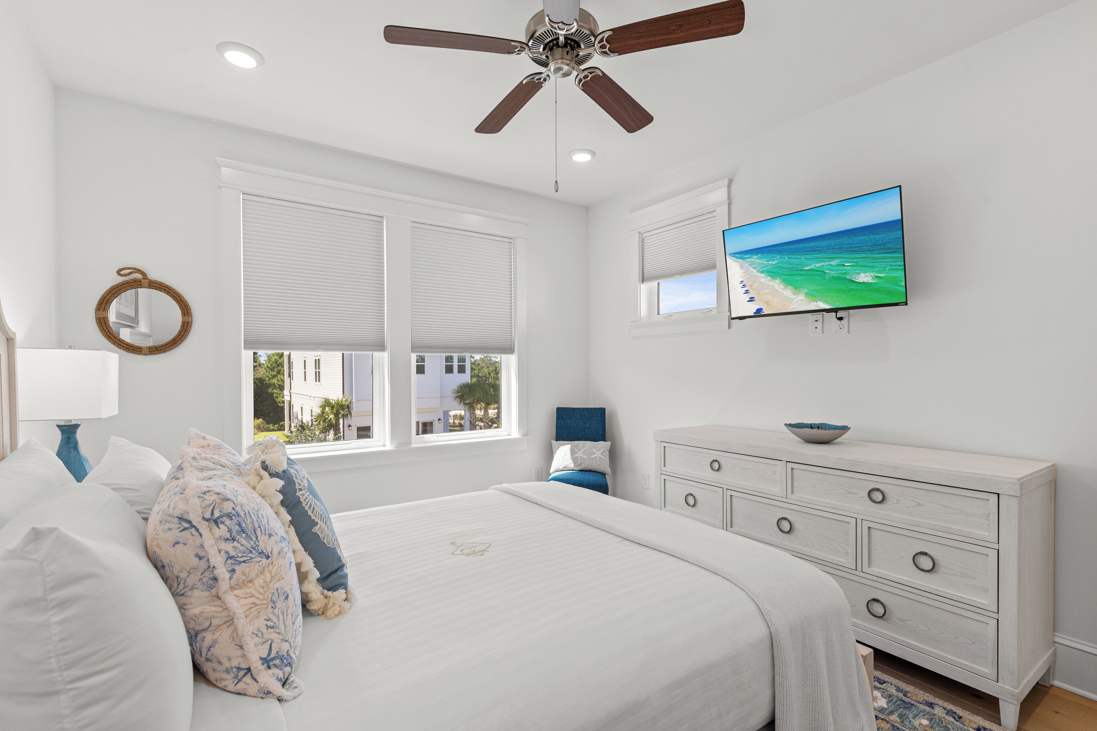 A bedroom with a bed, a dresser, a television, and a ceiling fan.
