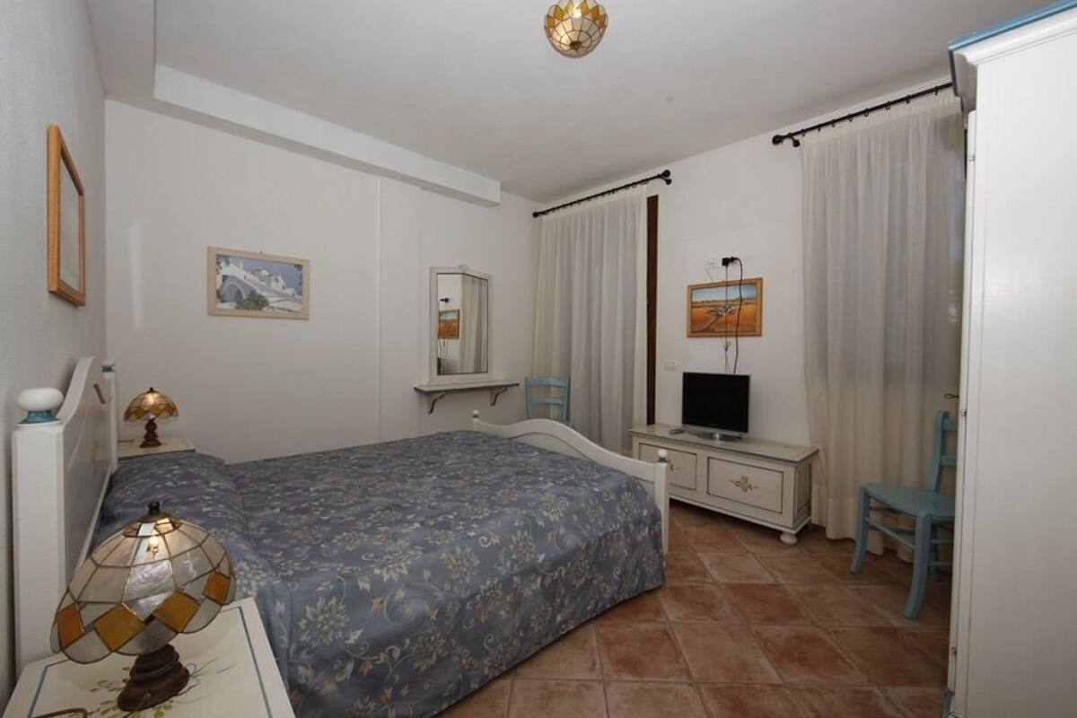 A bedroom with a bed, a television, a dresser, and a chair.