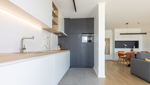 A modern kitchen with a built-in island, grey cabinets, and a stainless steel range hood. - Amazing Apartment With Sea-views (Middelkerke)