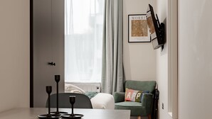 Uma sala de estar moderna com uma mesa de jantar, uma poltrona verde e um sofá.