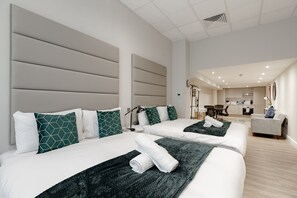 Una habitación de hotel con dos camas, kitchenette y zona de estar.