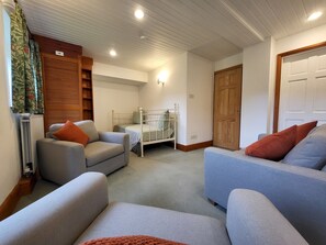 Ein gemütliches Wohnzimmer mit einem Bett, zwei Sofas, einer Heizung und einer Holztür.