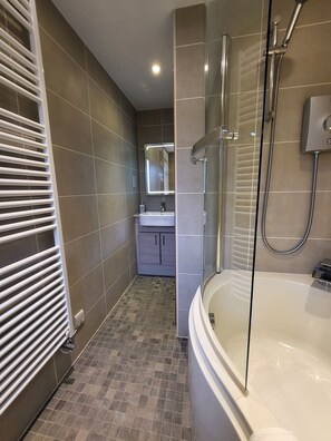 Ein modernes Badezimmer mit einer gläsernen Duschkabine, einer weißen Badewanne und einem Waschtisch mit Spiegel.