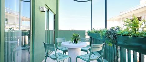 A balcony with a round table and chairs, a glass door, and a view of buildings.