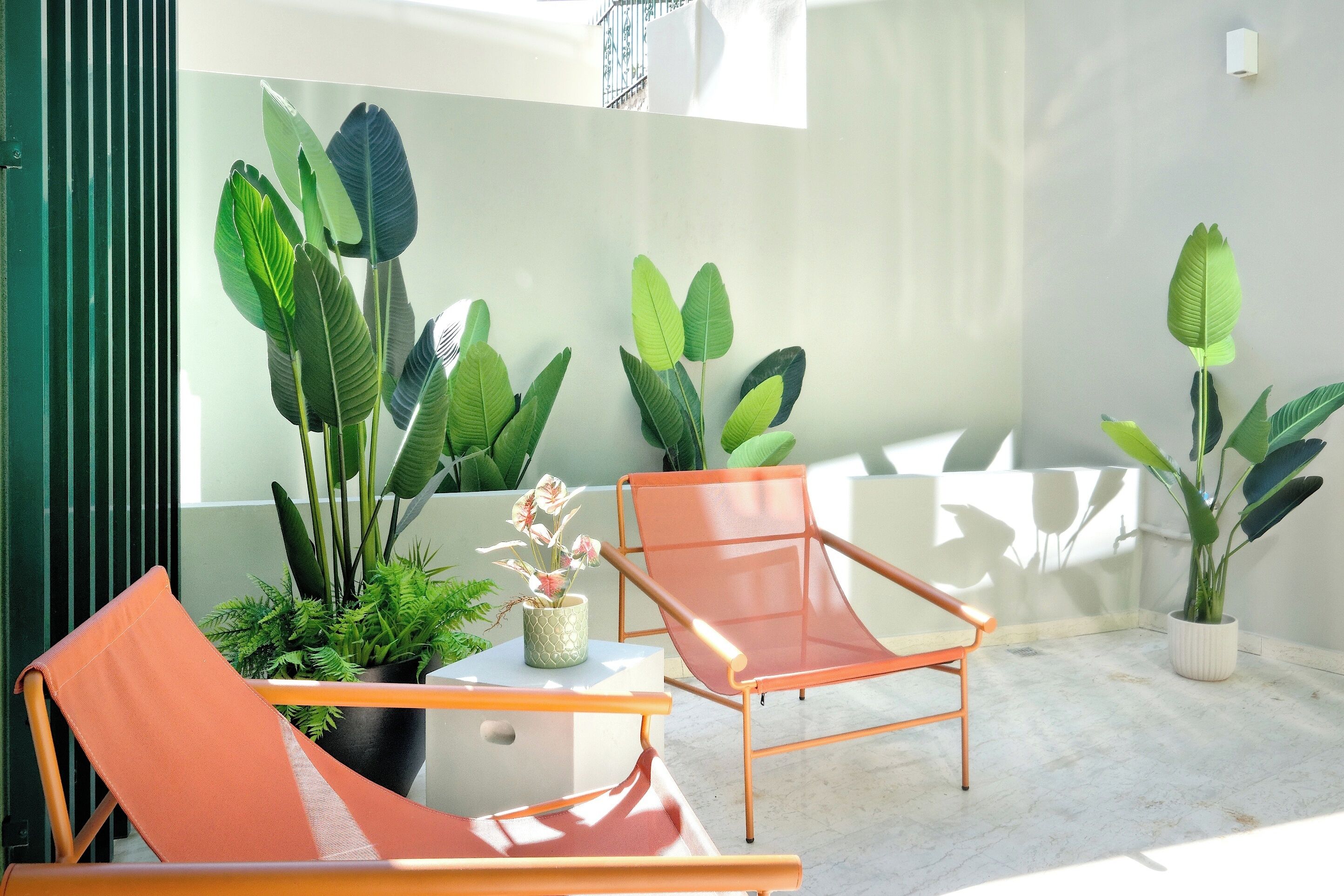 A modern outdoor seating area with two orange chairs and potted plants.