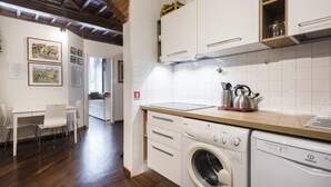 A kitchen with white cabinets, a washing machine, and a dining area with a table and chairs. - Sauro River View by MMega (Florence)