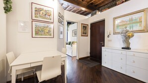 A dining area with a white table and chairs, framed artwork on the walls, and a wooden ceiling. - Sauro River View by MMega (Florence)