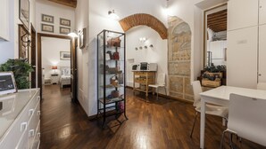 A modern interior with wooden flooring, a glass display cabinet, a white dining table, and a decorative archway. - Sauro River View by MMega (Florence)