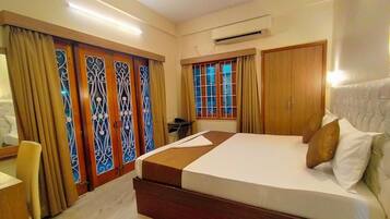 A hotel room with a large bed, wooden wardrobe, and a desk.